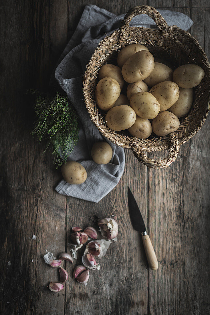 Kartoffeln und Knoblauchzehen auf rustikalem Holztisch