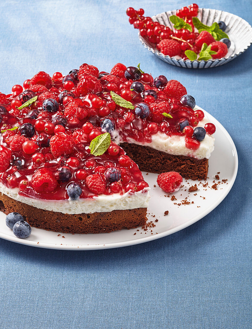 Browniekuchen mit Sauerrahmcreme und Sommerbeeren, angeschnitten