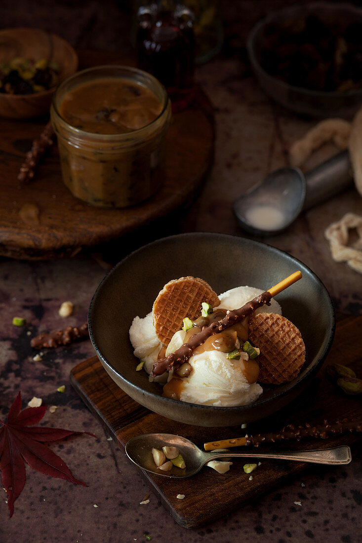Vanilla ice cream topped with caramel sauce, mini stroopwafel cookies, chopped nuts and a chocolate stick