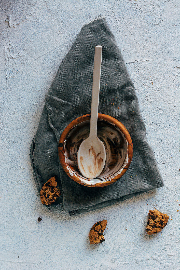 From above pieces of yummy oatmeal cookies placed on plaster surface near cloth napkin and empty bowl with stains of ice cream and spoon