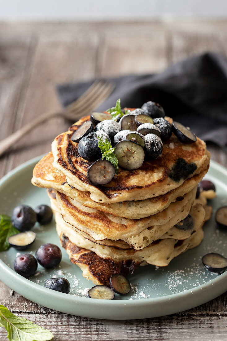 Blueberry pancakes with bluberries, icing sugar and mint