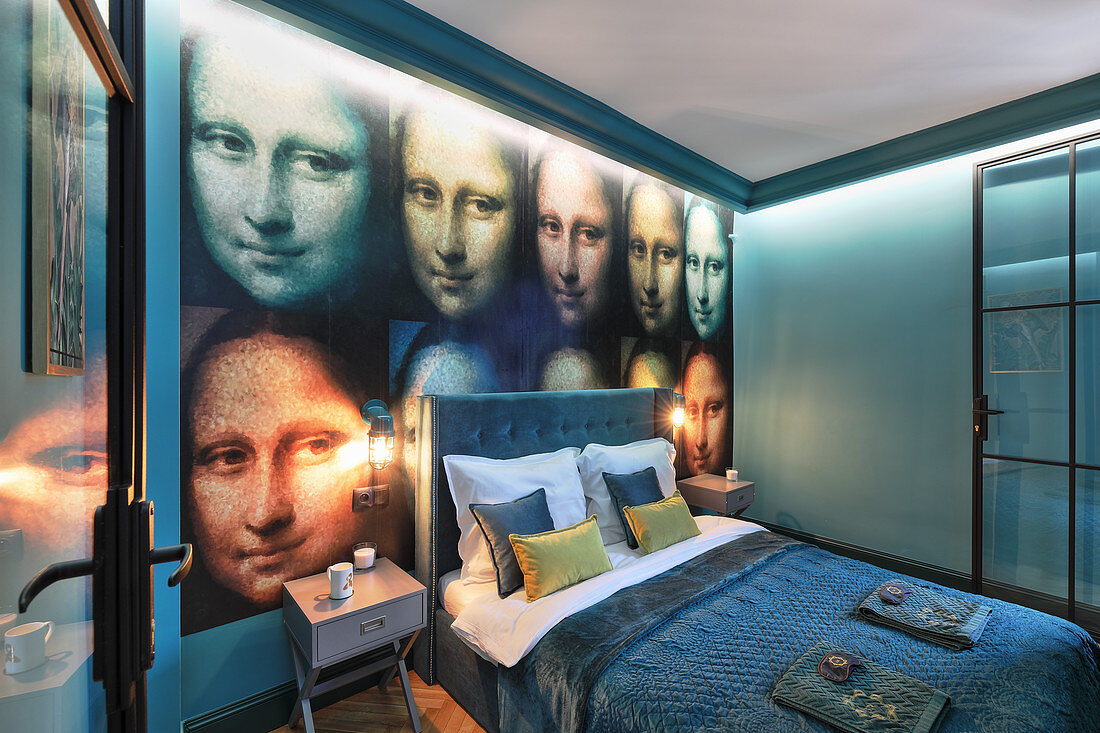 Petrol-blue bedroom with Mona Lisa wallpaper on wall behind bed