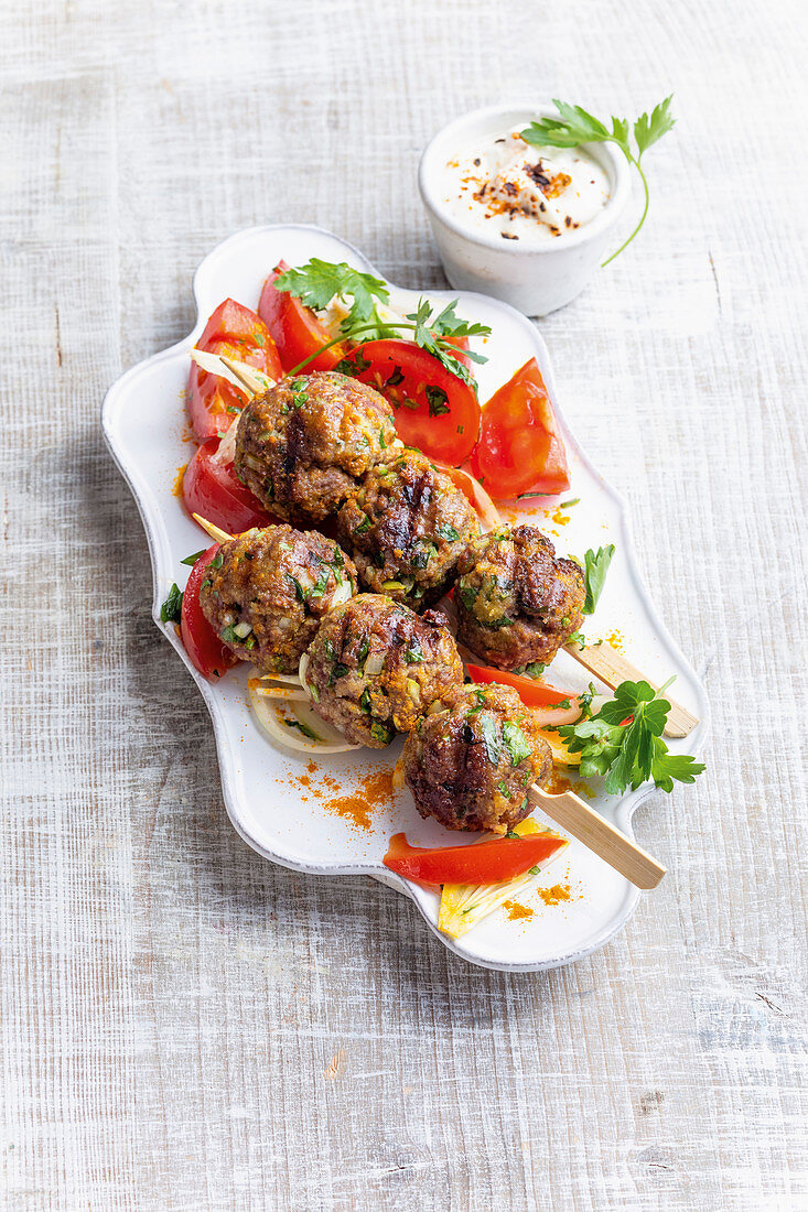 Oriental meatball skewers with tomato salad