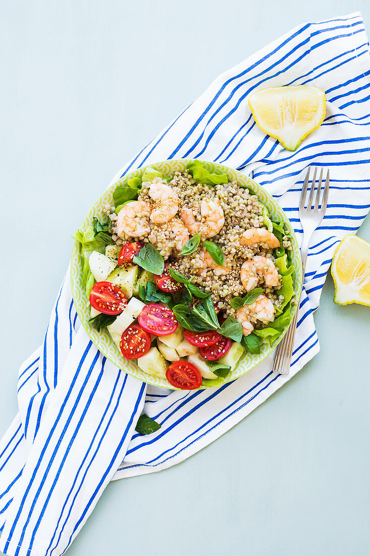 Light summer gluten free lunch bowl with buckweat, cucumber, tomatoes and prawns on lettuce leaves