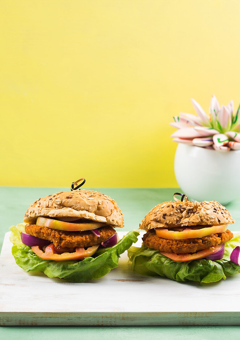 Veganer Burger: Dinkelbrötchen mit Soja-Gemüse-Patty, Salatblatt, Tomate und roten Zwiebeln