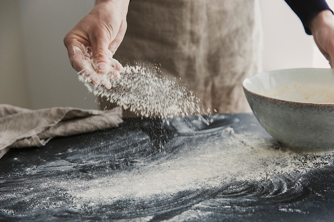 Mehl auf Küchenarbeitsfläche streuen