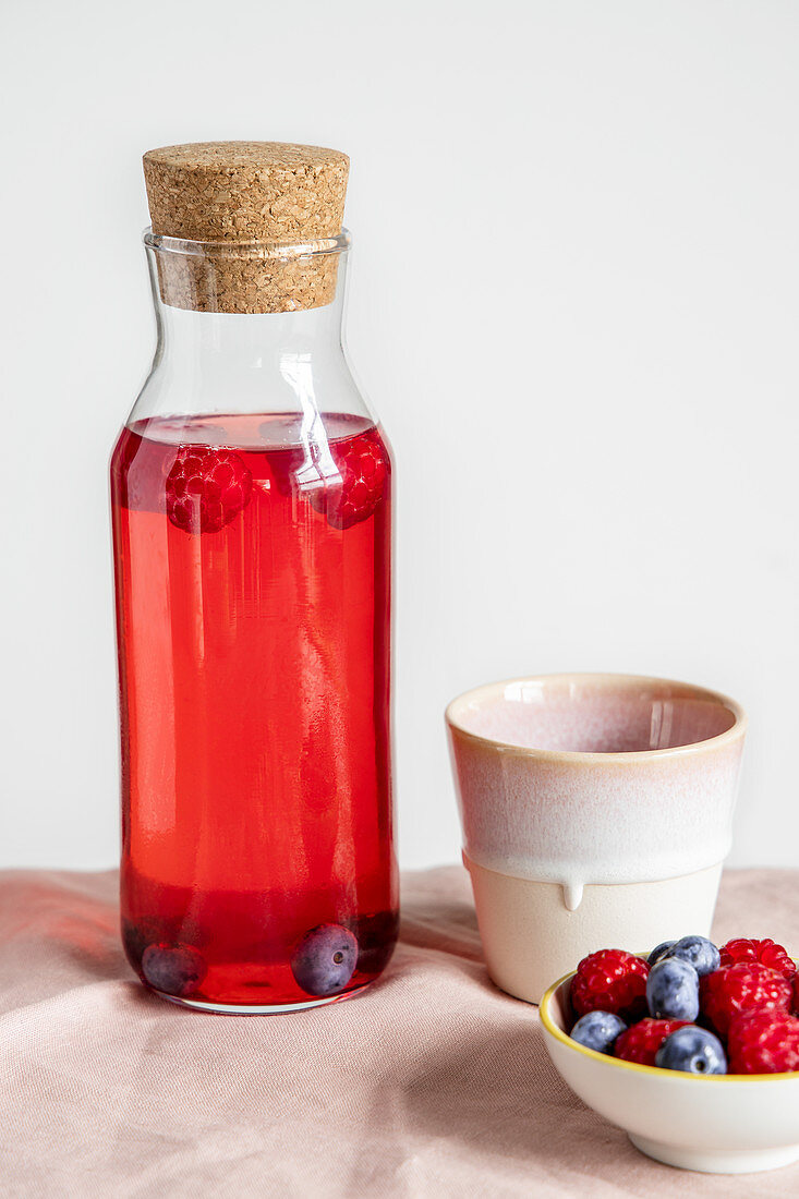 Summer drink with berries in a glass bottle