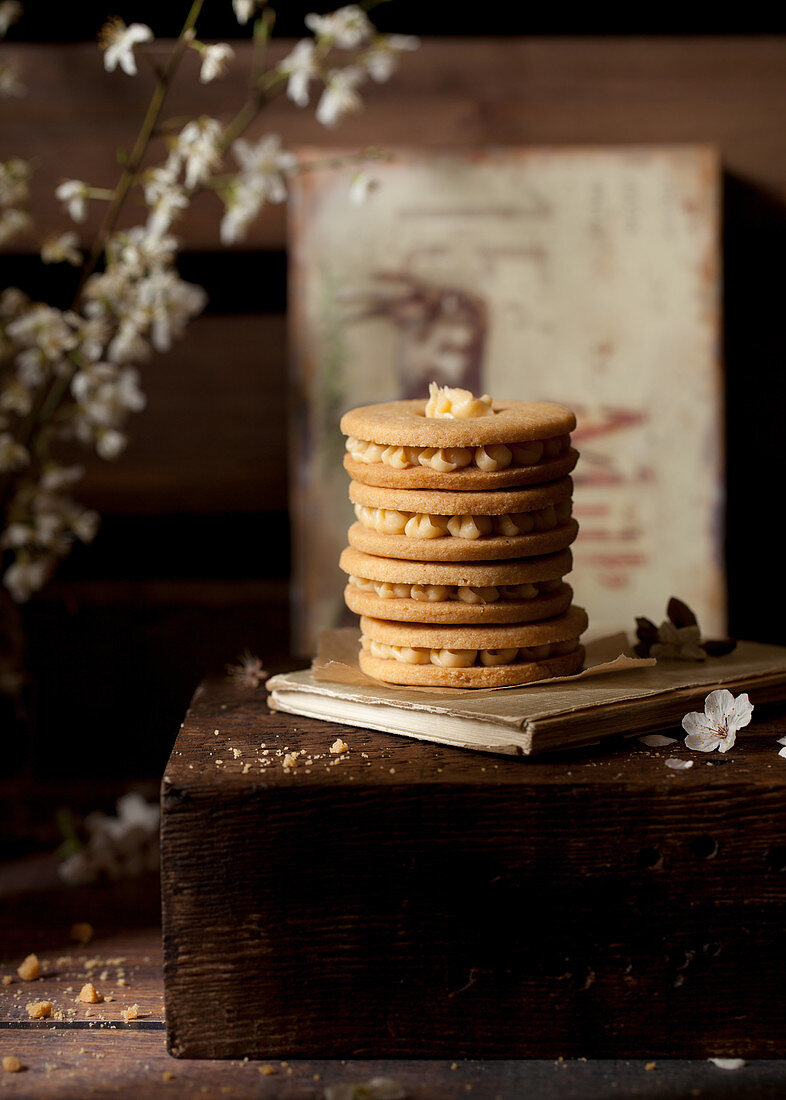 Stack of buttercream filled biscuits in a rustic setting