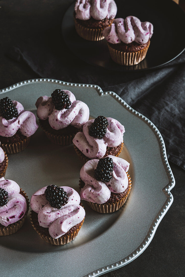 Chocolate cupcakes with black curant cream cheese frosting and decorated with blackberries