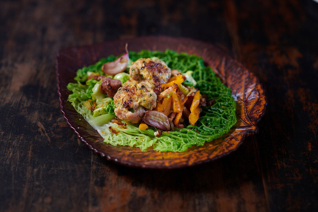 Savoy cabbage medley with garlic, sausage, bacon, peppers and veal meatballs on a savoy cabbage leaf