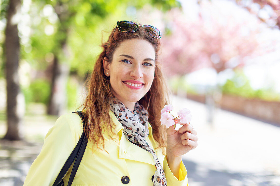 Happy young woman holding cherry blossom