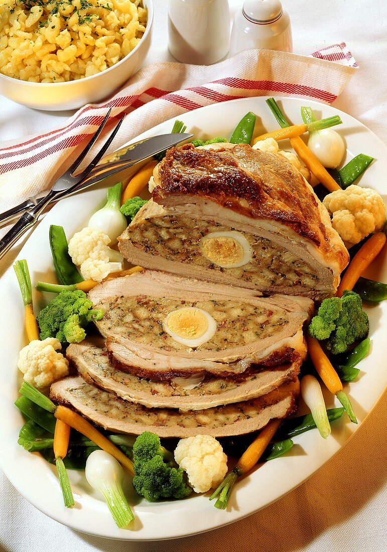 Stuffed veal breast with boiled egg and bowl of noodles