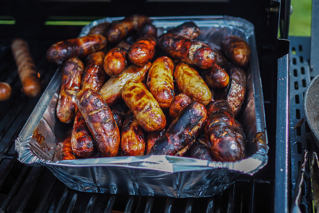 Sausages in an aluminium tray on a gas grill