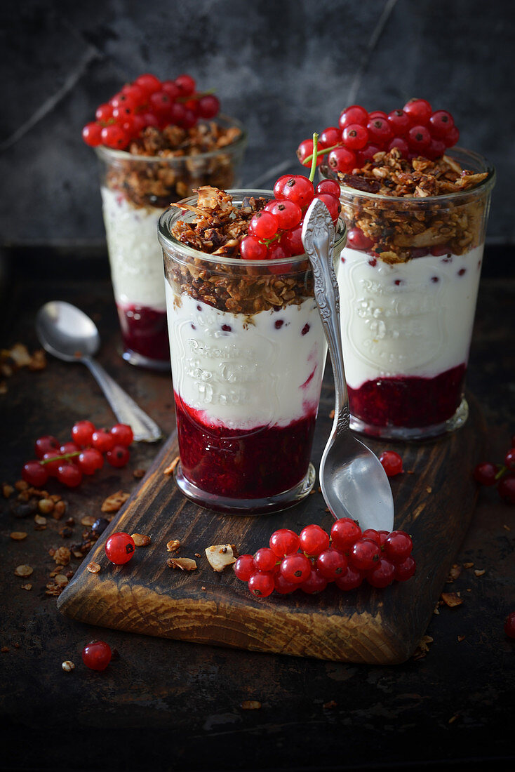 Joghurt mit Cerealien und roten Johannisbeeren im Glas