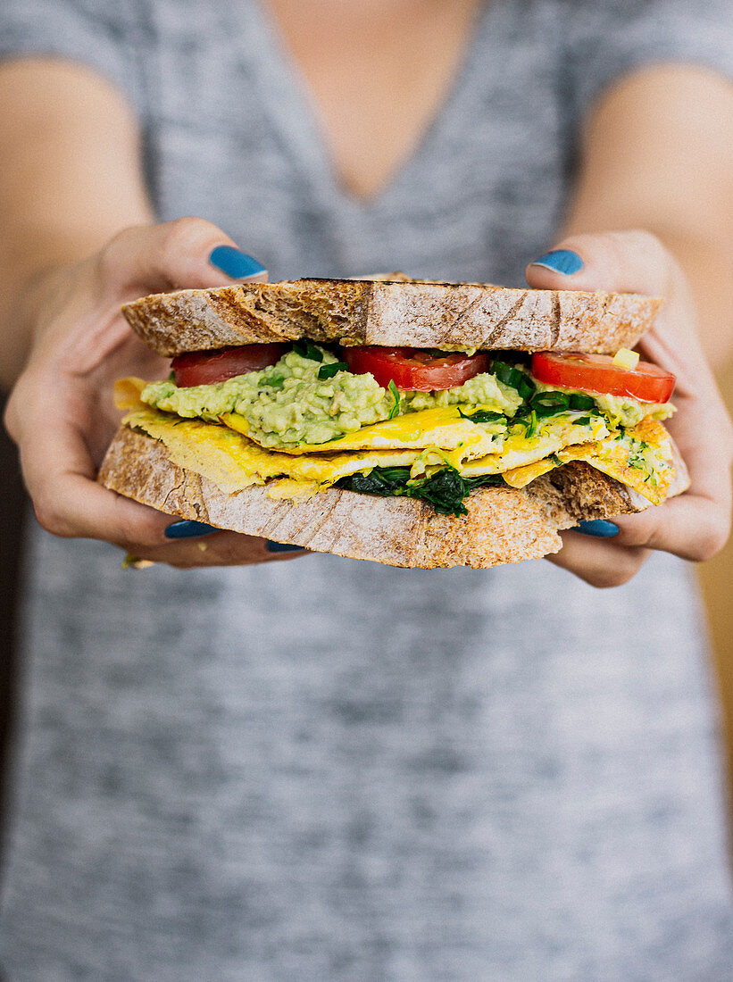 Woman holding omelette avocado sandwich