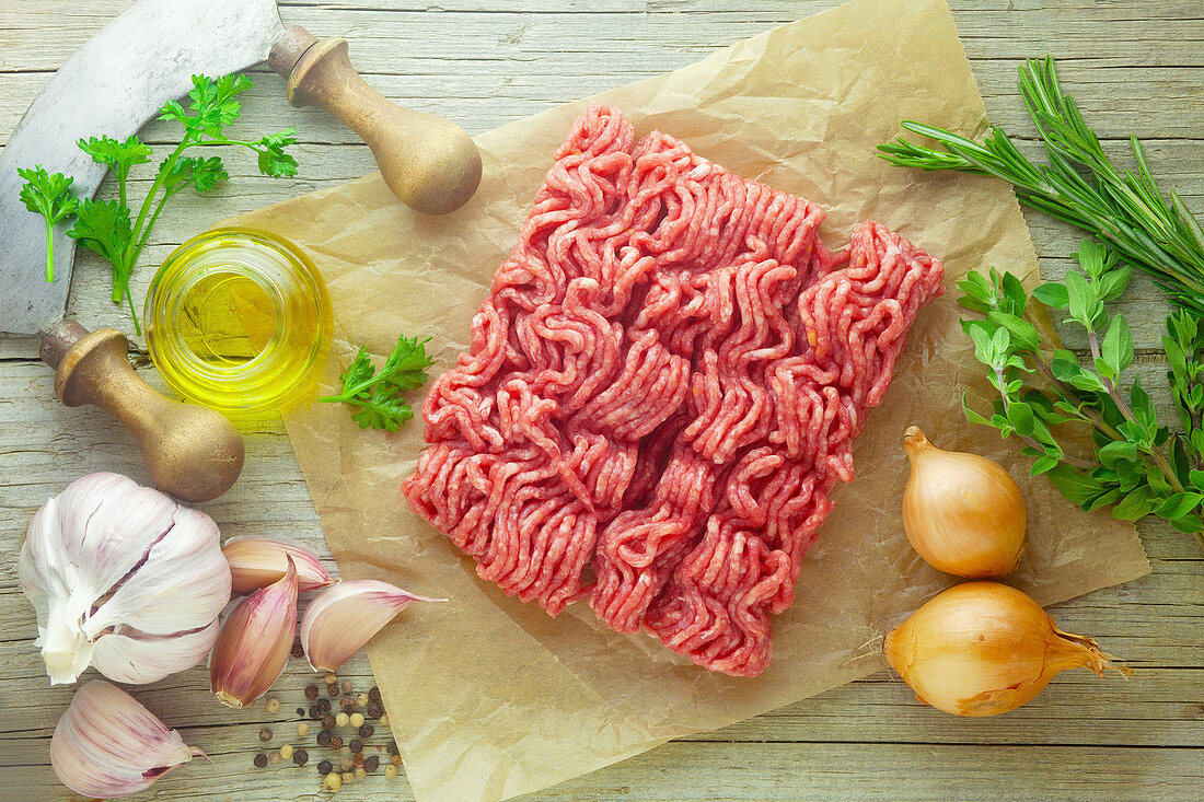 Raw minced meat with ingredients on a wooden surface