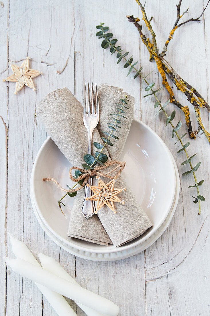 Festive place setting decorated with eucalyptus, straw stars and natural materials