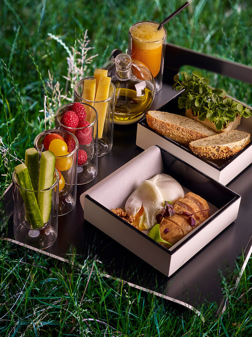 Picknick-Tablett mit Gemüse, Obst, Olivenöl, Brot, Hähnchen und Ei