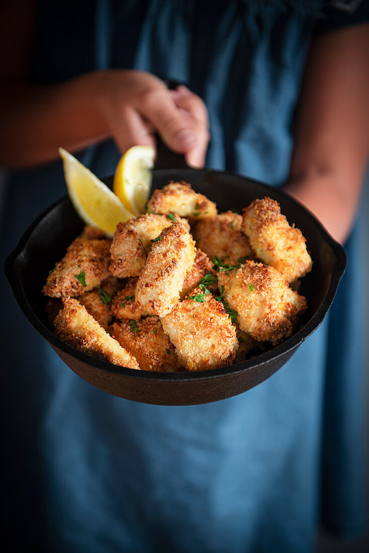 Frau hält Pfanne mit Chicken Nuggets