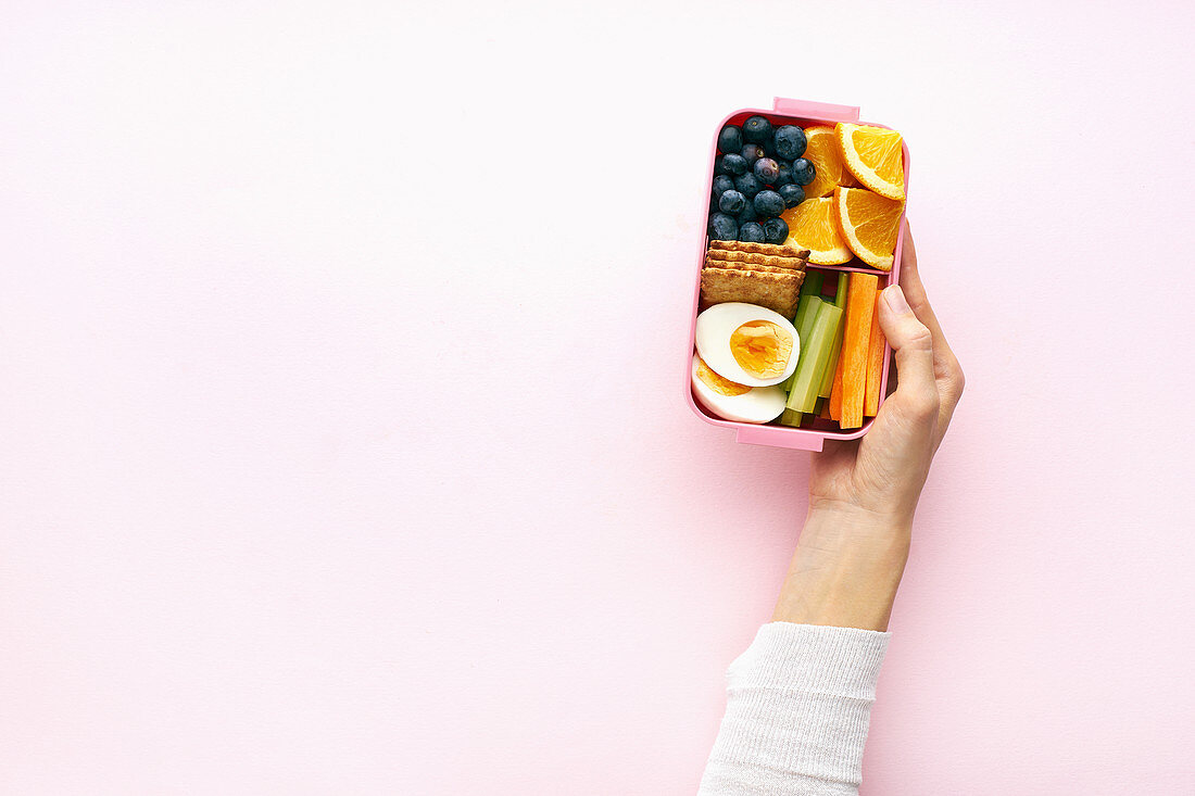 Frauenhand hält Lunchbox mit gesunden Snacks