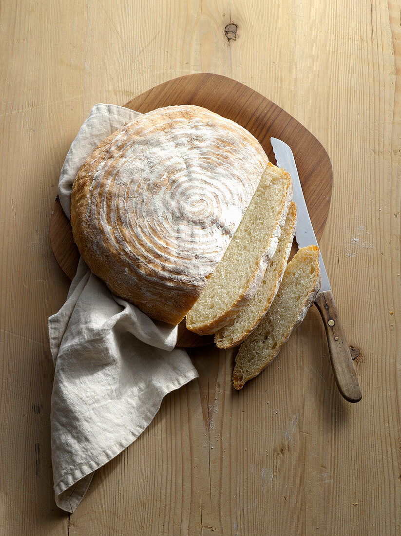 Ein Kartoffelbrot, angeschnitten auf Holzuntergrund