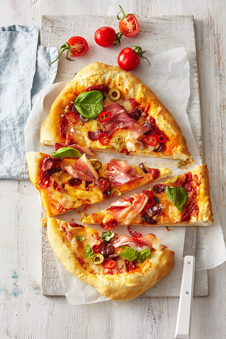 Italienische Pizza mit Parmaspeck und Oliven, in Stücke geschnitten