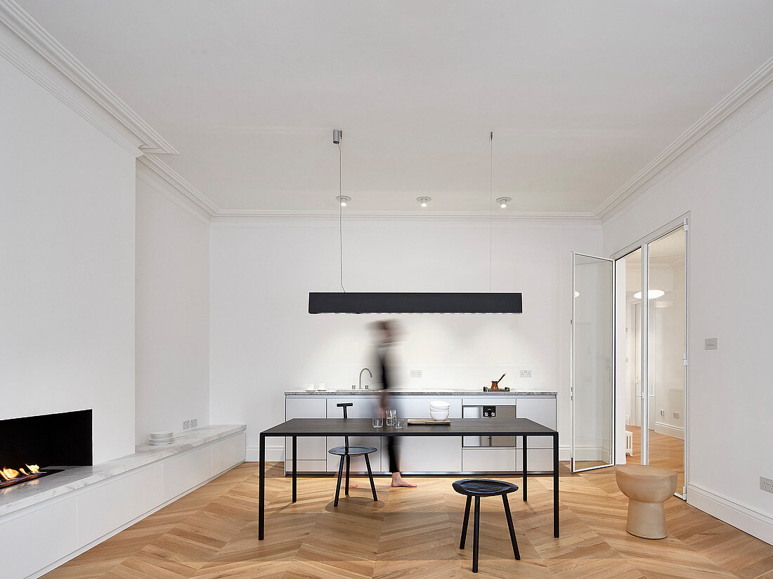 Kitchen counter, table and fireplace in open-plan interior with modern minimalist furnishings