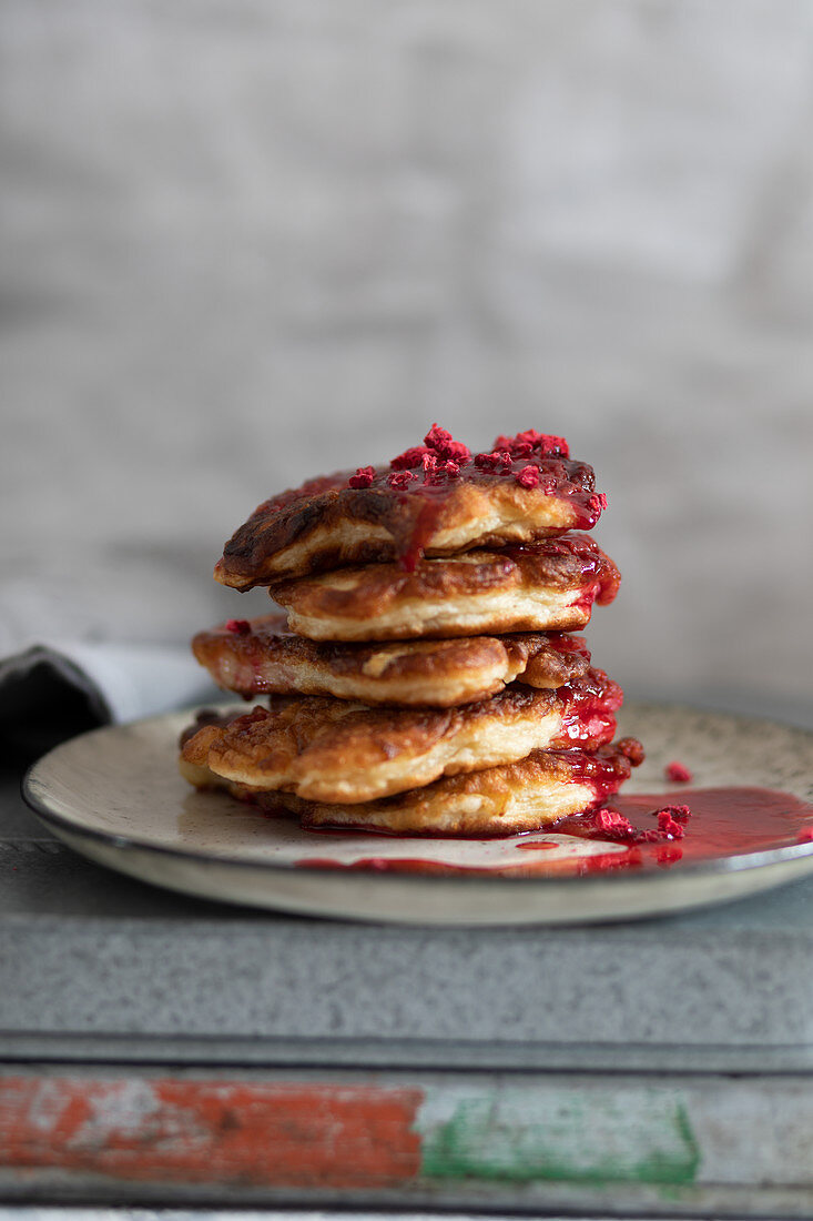 Stack of homemade fritters with raspberry coulis