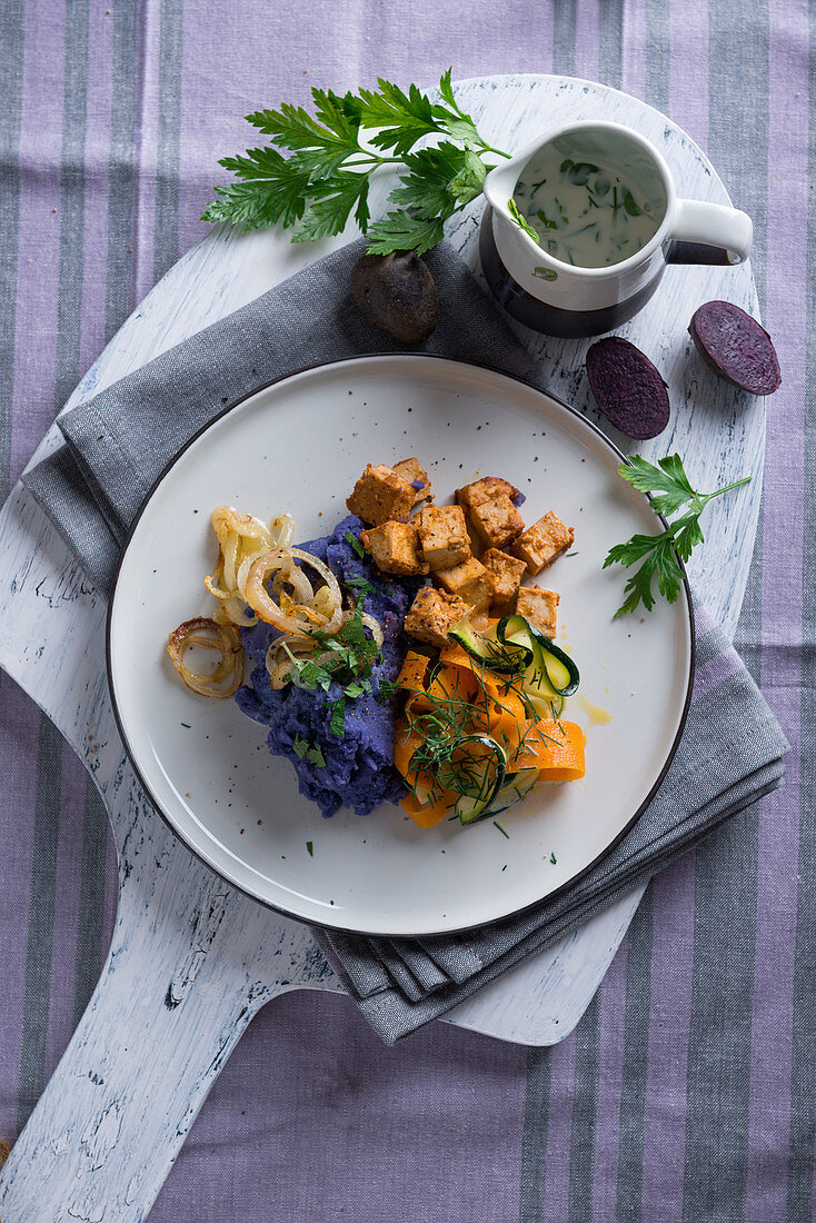 Veganer violetter Kartoffelstampf mit Zucchini-Möhren-Gemüse und Tofu