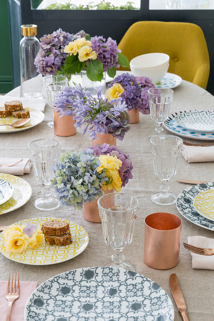 Sommerlich gedeckter Tisch mit gemusterten Tellern und Blumen