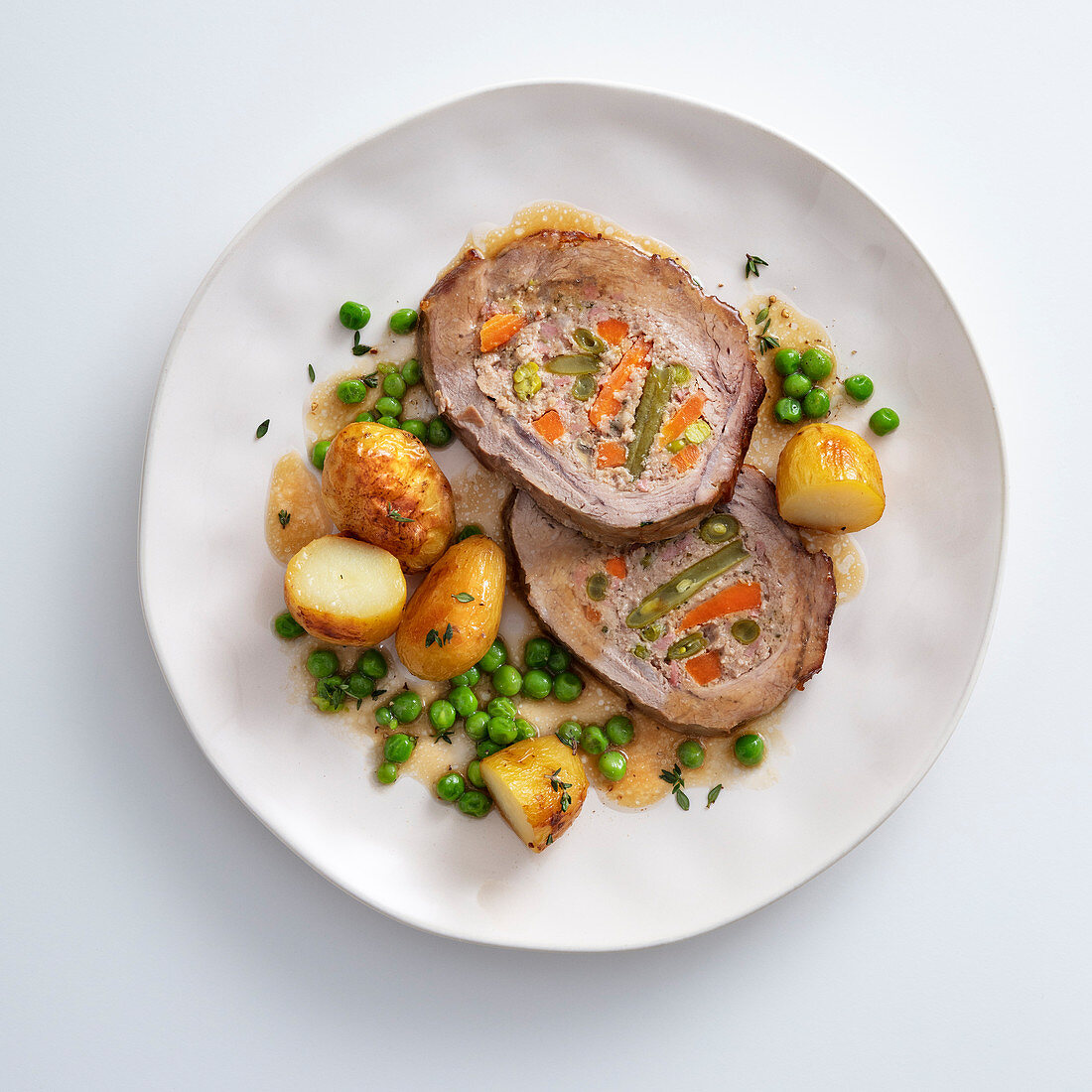 Stuffed roast veal with peas and potatoes