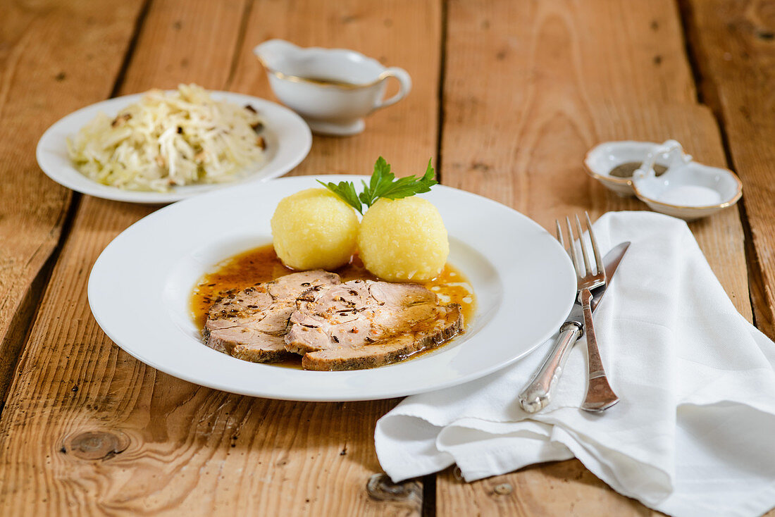 Schweinebraten in Scheiben mit Kartoffelklössen und Kraut