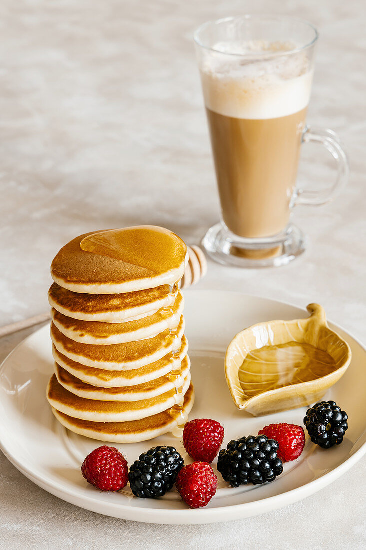 Pancakes mit Honig, Himbeeren, Brombeeren und Caffe Latte