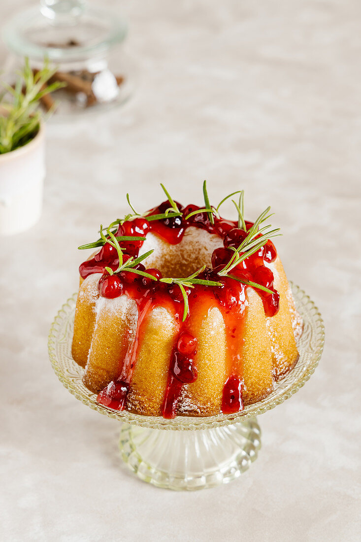 Vanilla bundt cake decorated with cranberry sauce and rosemary