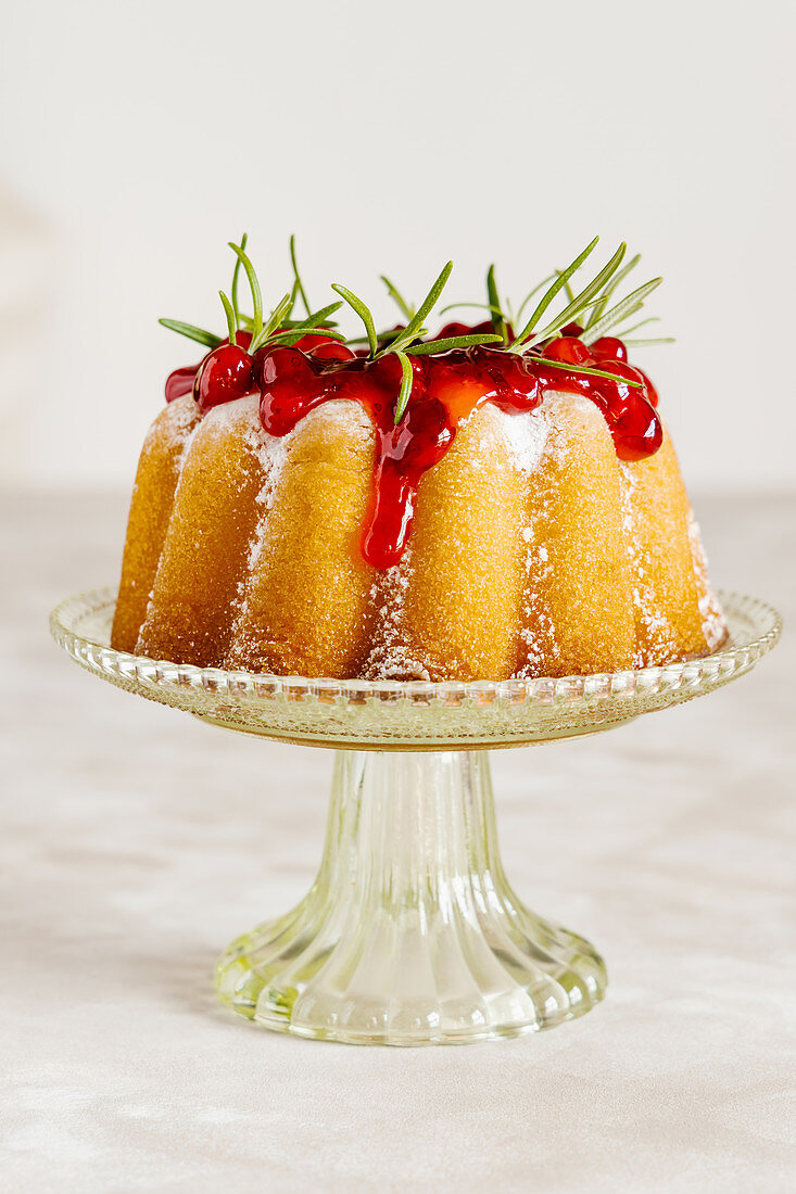 Vanilla bundt cake decorated with cranberry sauce and rosemary