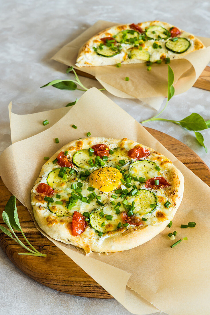 Pizza mit Zucchini, Tomaten, Eigelb, laktosefreiem Frischkäse und Mozzarella