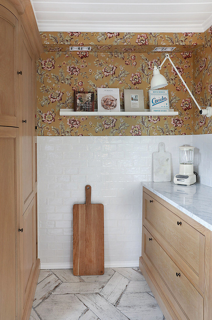 Modern kitchen with wooden cabinets and floating shelf on floral wallpaper