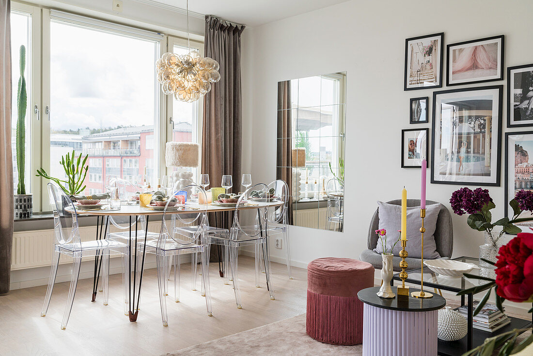 Essbereich mit DIY-Tisch und Plexiglas-Stühlen vor Fenster im Wohnzimmer