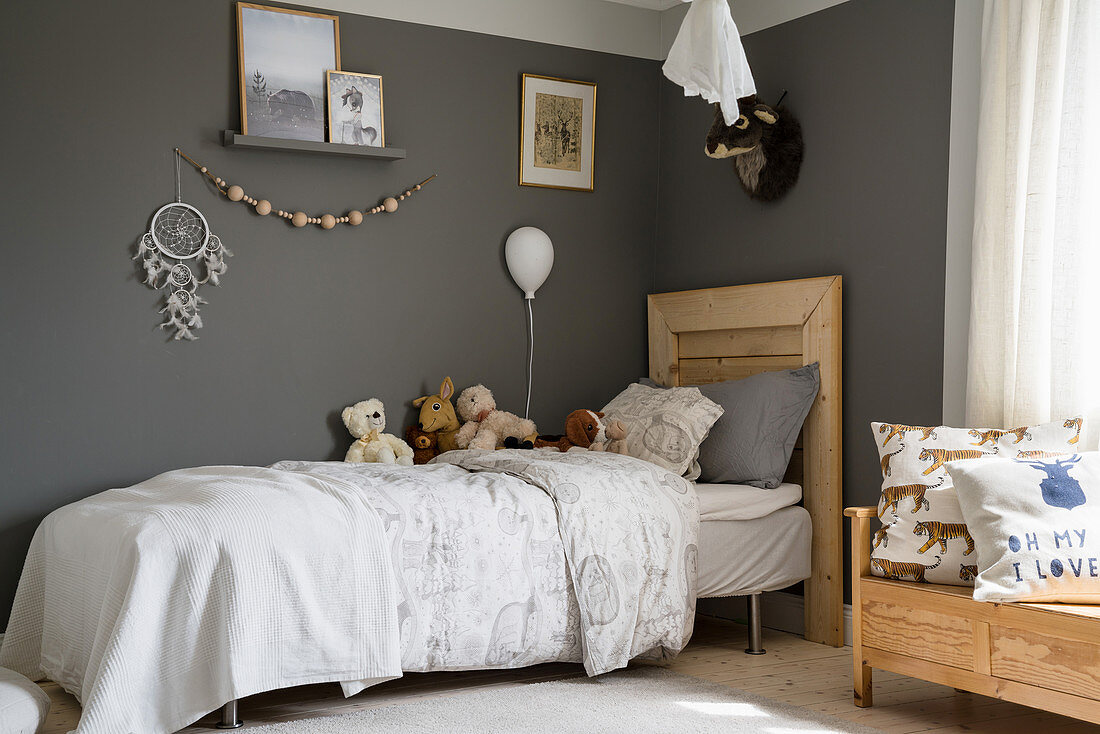 Bed with wooden headboard in child's bedroom with dark-painted walls