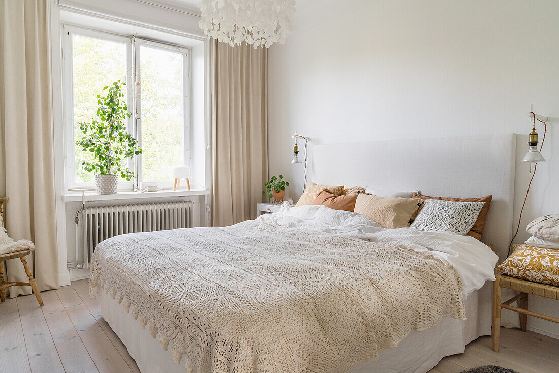 Doppelbett mit Leinenbezügen und gehäkelter Tagesdecke in hellem Schlafzimmer