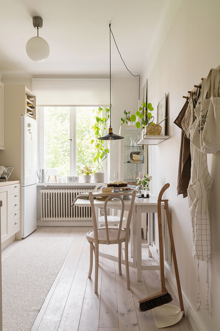 Table with two chairs in bright kitchen with white oiled wooden floor