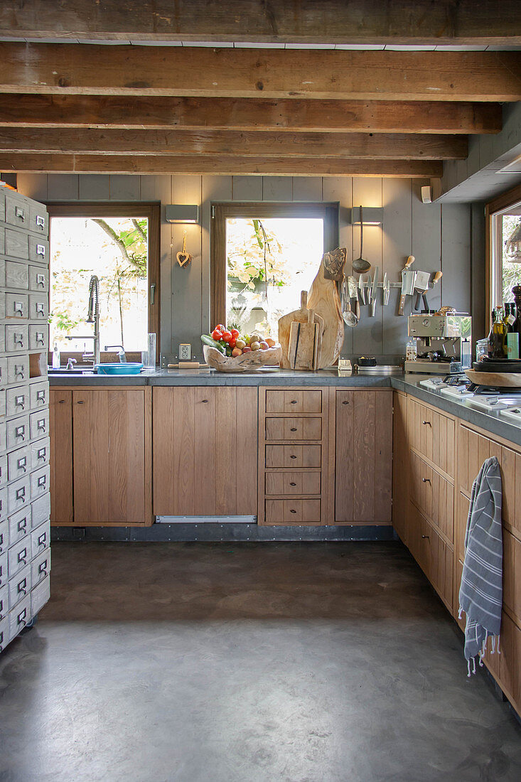 Modern country-house kitchen with wooden cupboards and wood-beamed ceiling