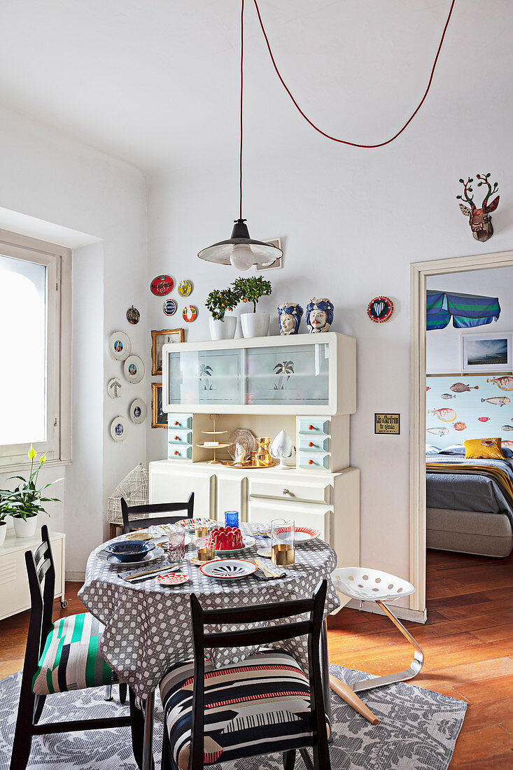 Set table, chairs with seat cushions and old dresser in dining room