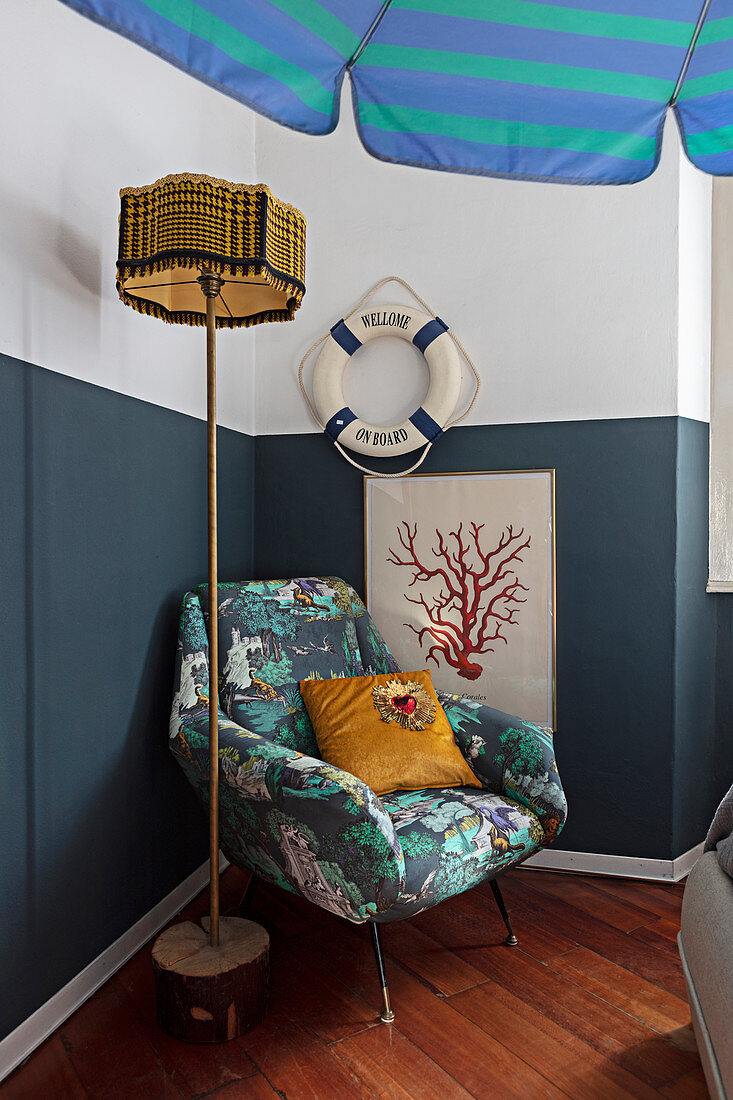 Armchair and maritime accessories on and against wall with blue painted dado
