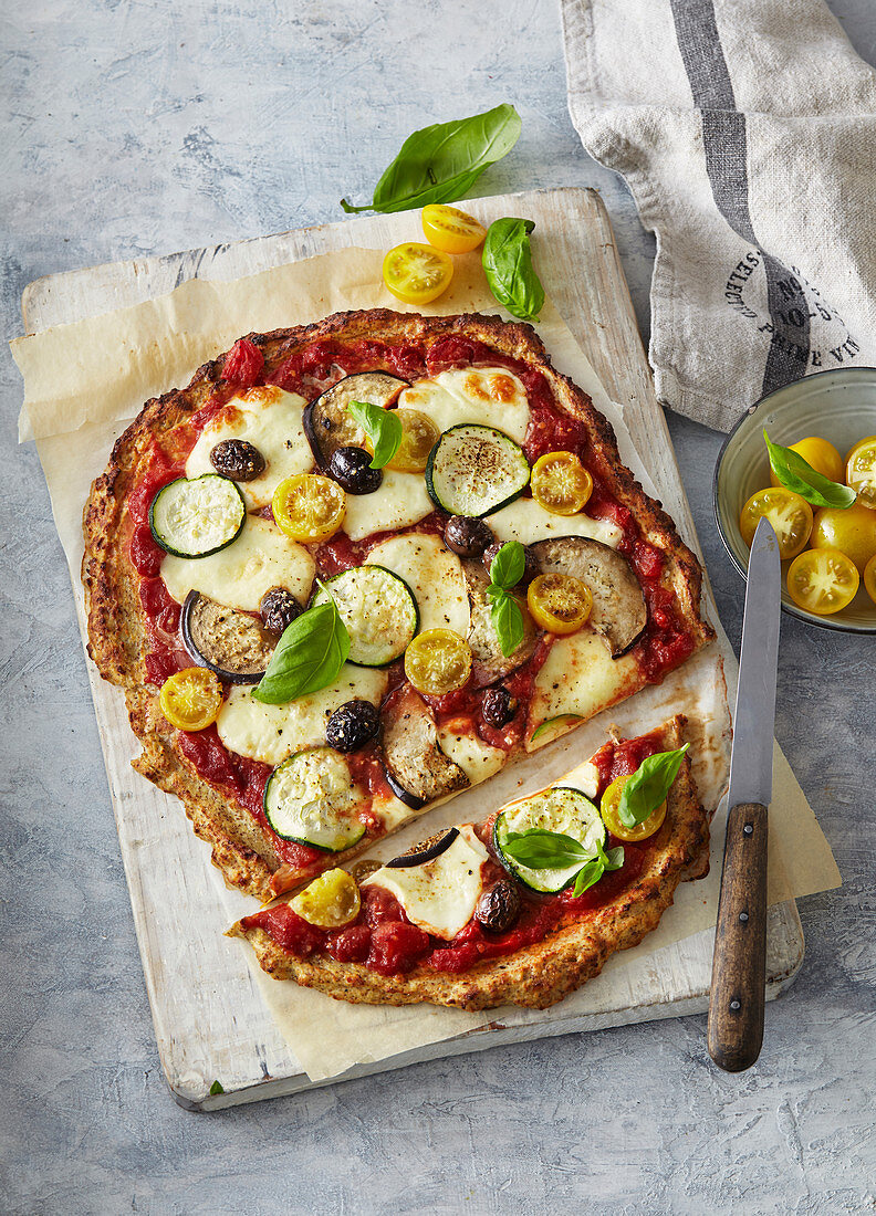 Vegetarische Pizza mit Zucchini, Auberginen, Kirschtomaten und Oliven