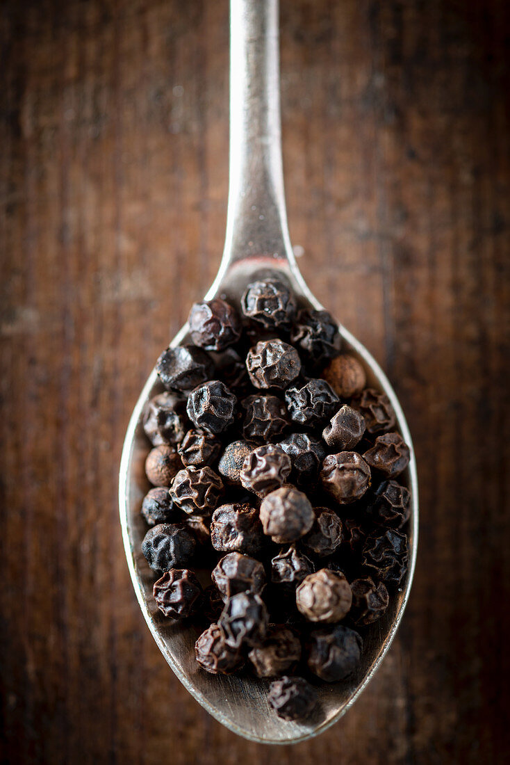 Black peppercorns on a spoon