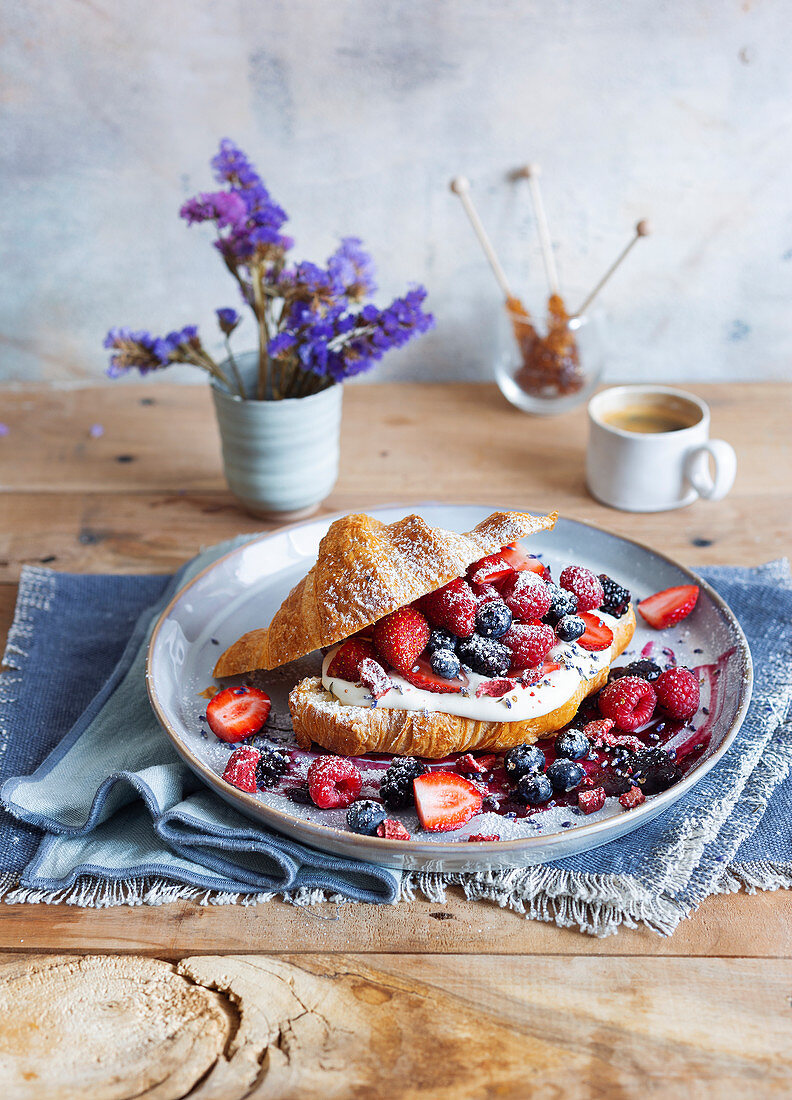 A croissant with cream, lavender cream and fresh berries