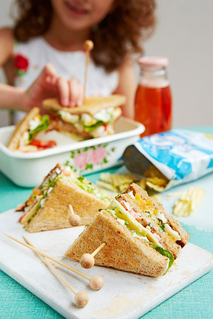 Girl eating egg and cress club sandwich