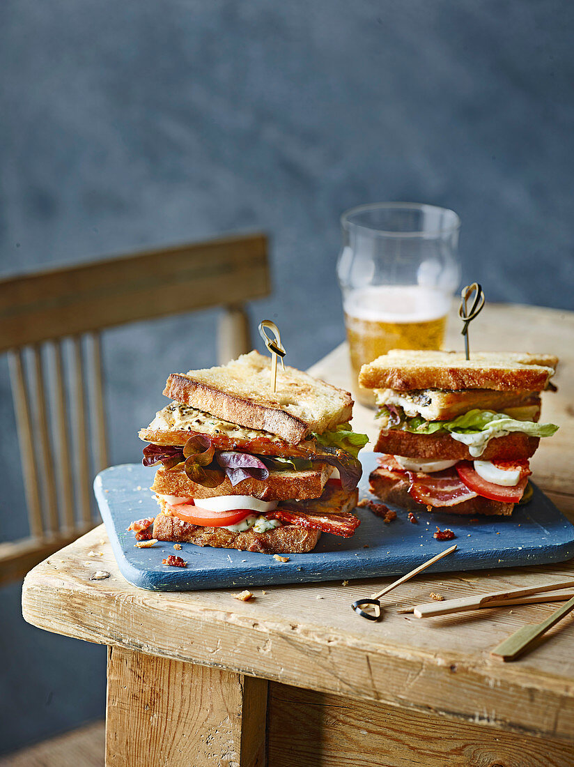 Club-Sandwiches mit Makrele auf rustikalem Holztisch
