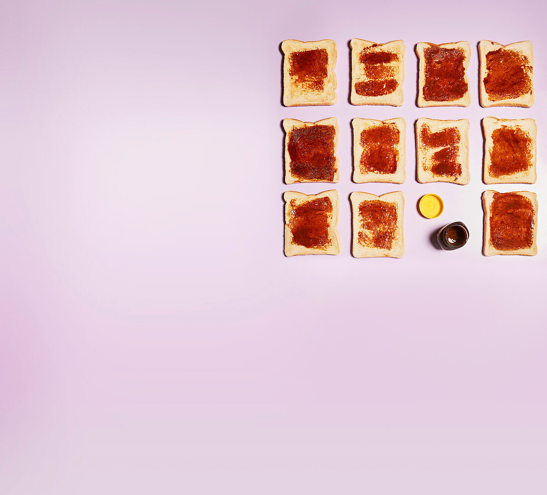 Mehrere Toast mit Marmelade aufgereiht auf rosa Untergrund